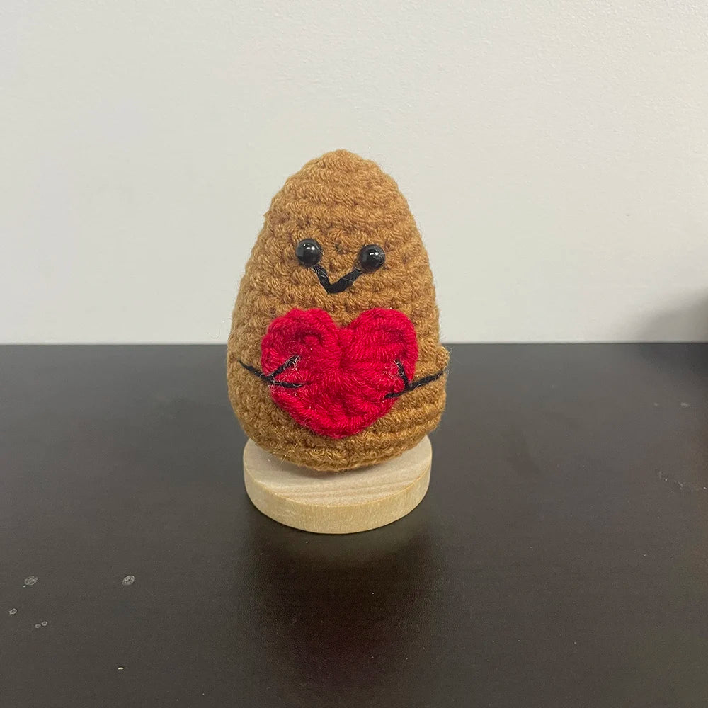 Handmade crochet potato plush doll with a stitched red heart and smiling face, holding arms out for a hug